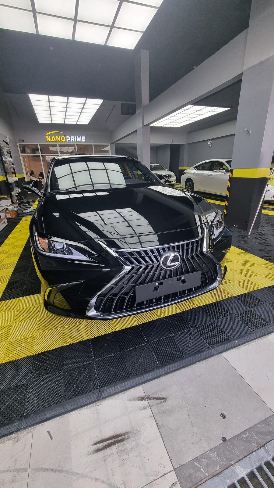 مقدمة سيارة سيدان سوداء بانعكاسات إضاءة الورشة